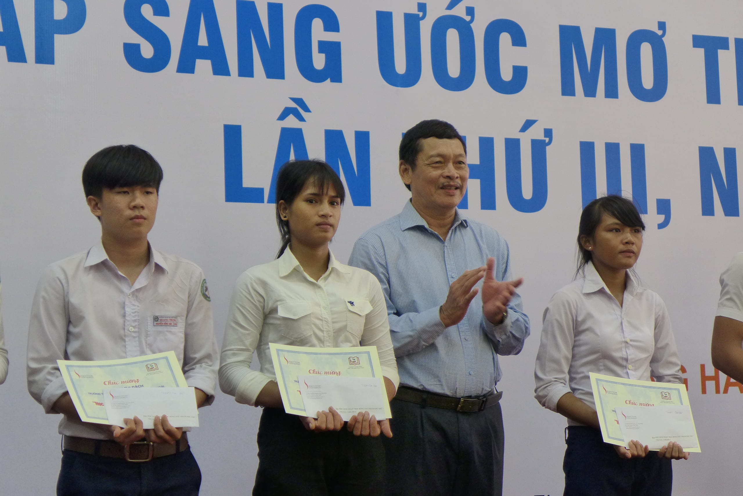 Nhà báo Quốc Vĩnh, Chủ tịch Hội Đồng hương Quảng Ngãi, chủ nhiệm CLB Doanh nhân Quảng Ngãi tại TP.HCM, trao học bổng cho các em học sinh Quảng Ngãi. Ảnh: XH